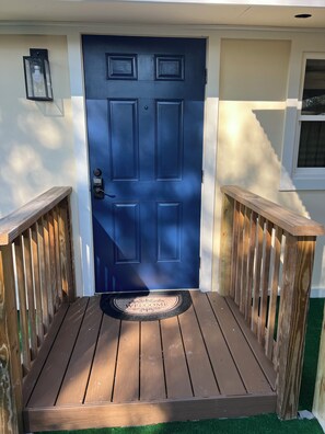 A blue door with a keypad lock, a welcome mat, and wooden railings. - Your Tampa Getaway 3 Minutes from Hard Rock Casino (Tampa)