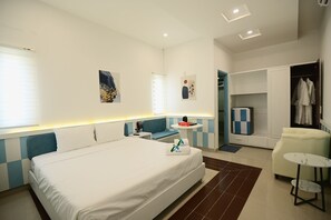 A modern hotel room with a large bed, a desk, a chair, a small table, and a wardrobe. - A Hotel (Da Nang)