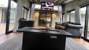 Ein modernes Wohnzimmer mit Flachbildfernseher, Ledersofas und einer Glastür zum Außenbereich.