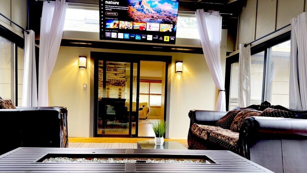 Eine moderne Lobby mit einem großen Flachbildfernseher, der einen Naturkanal zeigt, bequemen Sitzgelegenheiten und einem Glastisch.