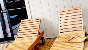 Zwei Holz-Loungestühle mit Metallbeinen auf einer Holzterrasse.