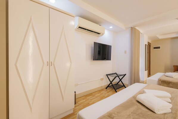 A hotel room with a wardrobe, a TV, a bed with towels, and a wall-mounted air conditioner. - Skypark Bay Hotel (Parañaque)