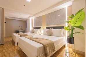 A hotel room with two beds, a bedside table, a potted plant, and a view of the hallway. - Skypark Bay Hotel (Parañaque)