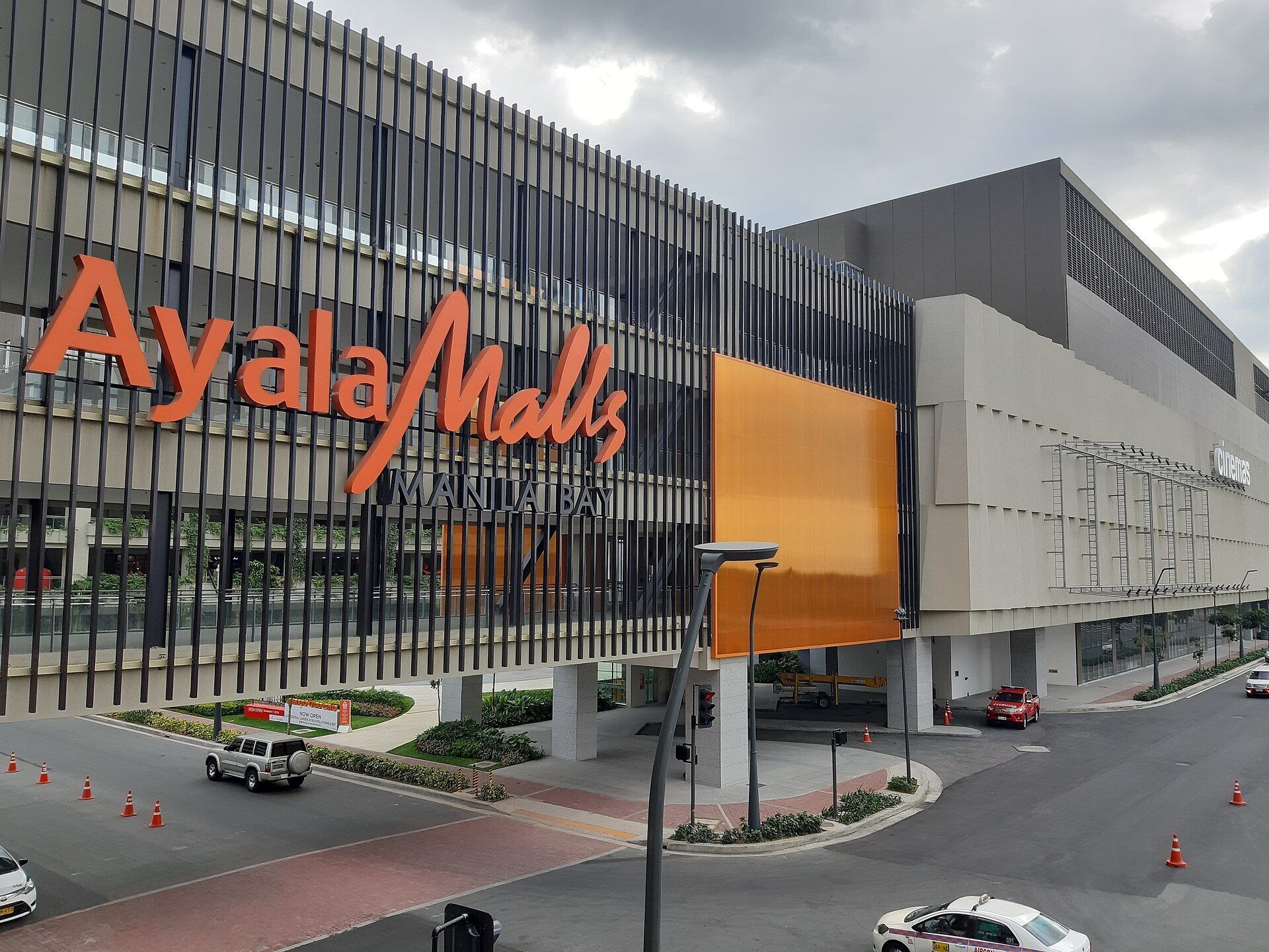 A modern building with the sign "AyalaMalls Manila Bay".