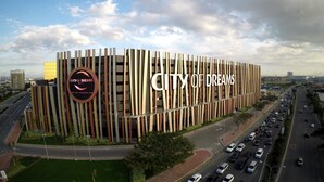 A modern building with a vertical striped facade and a prominent 'City of Dreams' sign. - Skypark Bay Hotel (Parañaque)