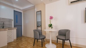 A modern kitchen with a wooden floor, a blue door, and a white round table with two grey chairs. - Skypark Bay Hotel (Parañaque)