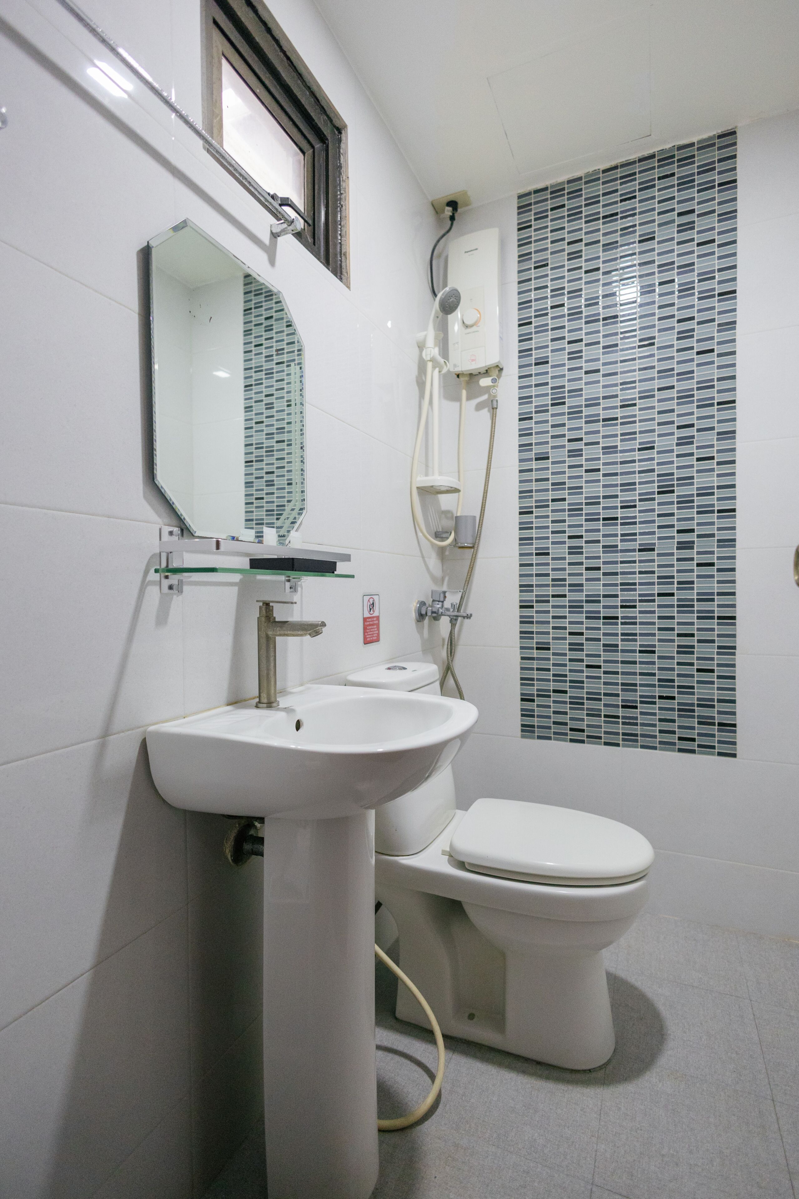 Et badeværelse med vask, toilet, spejl og brusebad.