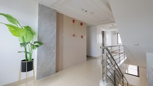 A modern hotel corridor with a potted plant, a marble wall, and a staircase. - Skypark Bay Hotel (Parañaque)