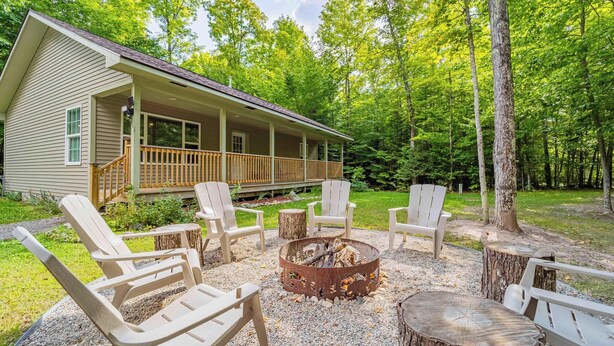 A cabin with a porch, outdoor seating, and a fire pit.