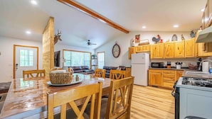 A spacious kitchen with wooden cabinets, a dining area with a wooden table and chairs, and a living room with a sofa and a fireplace.