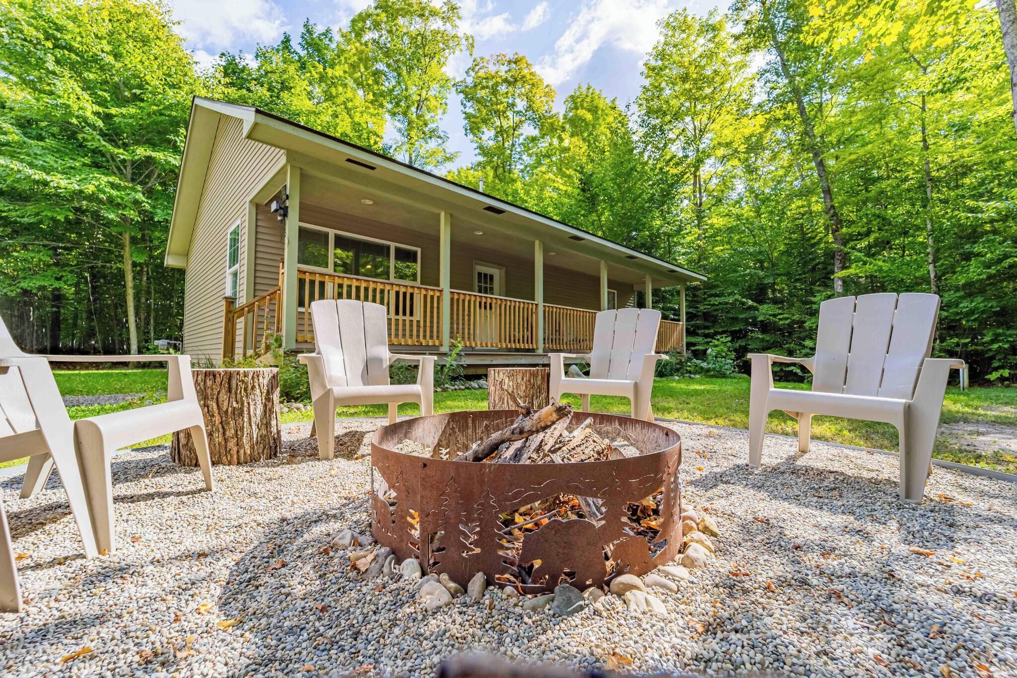 Une cabane dotée d’une véranda, d’un espace salon extérieur et d’un foyer.