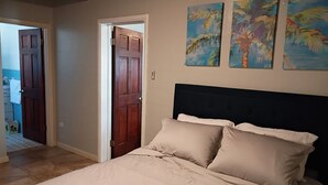 A bedroom with a bed, a wooden door, and two wall paintings. - Beautiful 2/2 Cottage waterfront property on Lake Jackson in Sebring FL. (Sebring)