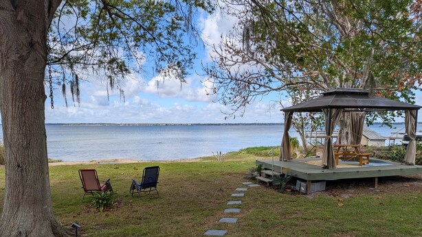 A gazebo with a view of the water, two chairs, and a stone pathway. - Beautiful 2/2 Cottage waterfront property on Lake Jackson in Sebring FL. (Sebring)