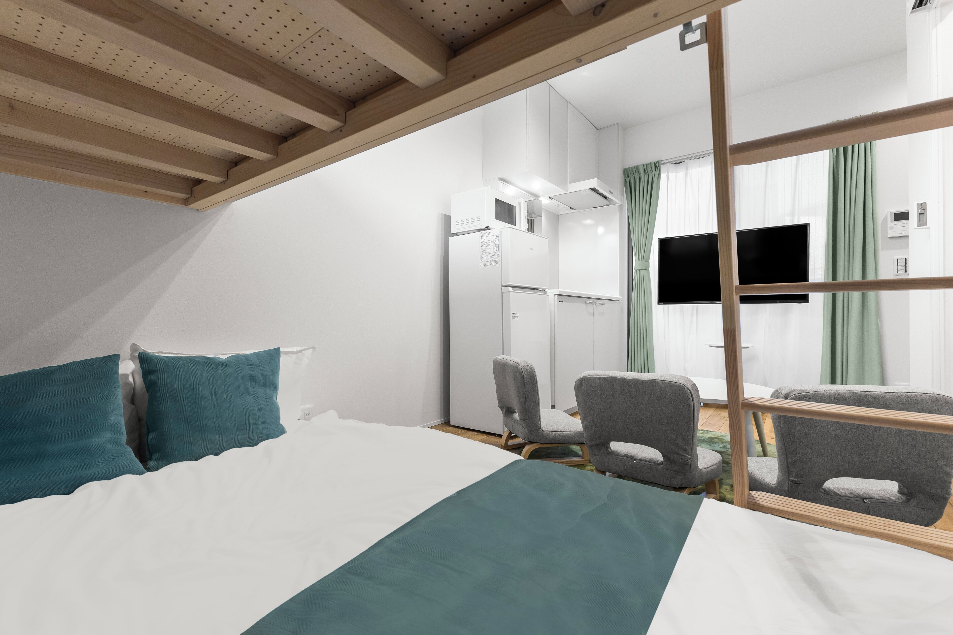 A hotel room with a bed, a desk, a chair, a television, and a window with curtains.