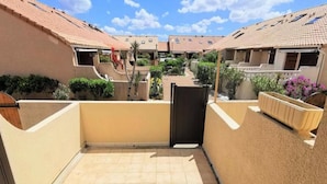 A courtyard with a tiled floor, a black gate, and a beige wall. - Houses & Villas for 6 People (Leucate)