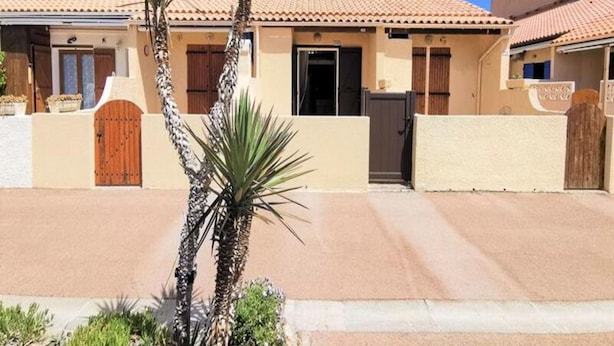 A building with a tiled roof, a wooden door, and a gate. - Houses & Villas for 6 People (Leucate)