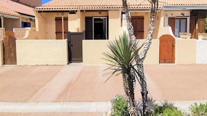 A residential building with a tiled roof, a gated entrance, and palm trees in the foreground. - Houses & Villas for 6 People (Leucate)