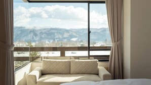 A hotel room with a large window, a bed, and a sofa. - Hotel Goryukan (Hakuba)