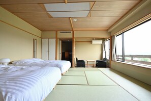 Ett hotellrum med två sängar, en sittgrupp med bord och stolar samt ett stort fönster.