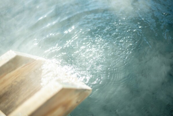 Una estructura de madera parcialmente sumergida en el agua, con ondulaciones y burbujas visibles en la superficie.