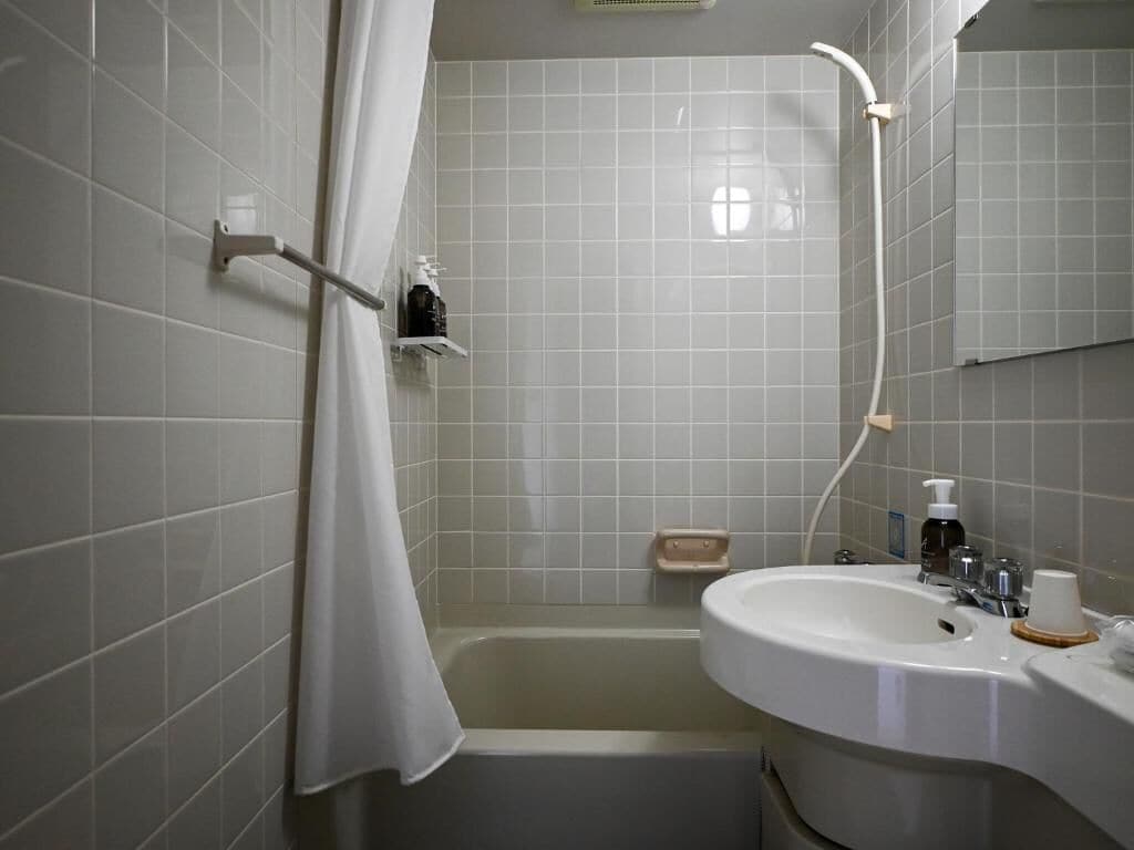 A bathroom with a bathtub, a sink, and a mirror.