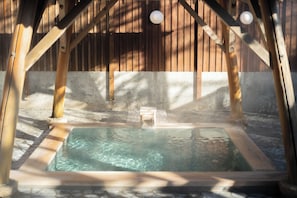 Un jacuzzi en una estructura de madera con suelo de hormigón.