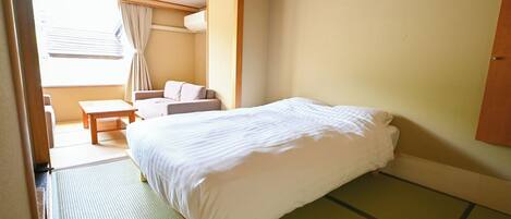 A room with a bed, a small table, a chair, and a window with curtains.