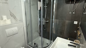 Een moderne badkamer met een douchekabinet van glas, een wit toilet en een wastafel met spiegel.
