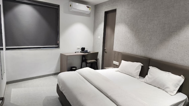 Et moderne hotelværelse med en stor seng, et skrivebord, en stol og et vindue.