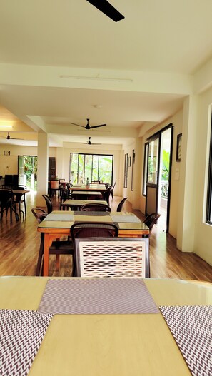 A spacious dining area with a high ceiling, large windows, and a ceiling fan.