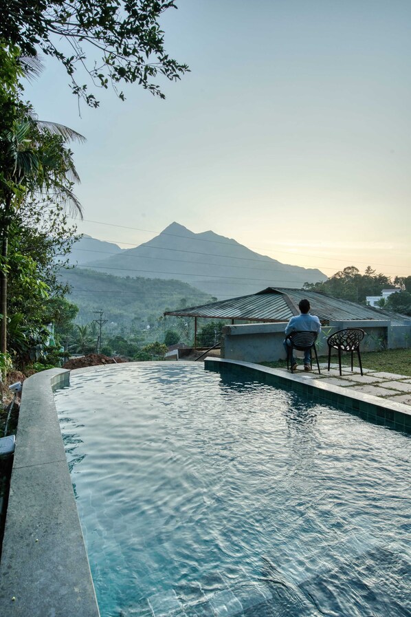 Une personne assise au bord d’une piscine, avec une vue sur les montagnes.
