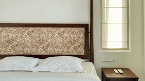 A bedroom with a bed, a nightstand, a wall-mounted air conditioner, a window with blinds, and a framed floral artwork. - Maison Claire Service Villa Wayanad – 4BR Stay Near Attractions (Kottappadi part, Wayand)