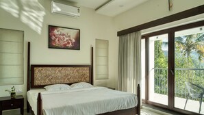 A bedroom with a large bed, a nightstand, a wall-mounted air conditioner, a window with curtains, and a balcony with a chair. - Maison Claire Service Villa Wayanad – 4BR Stay Near Attractions (Kottappadi part, Wayand)