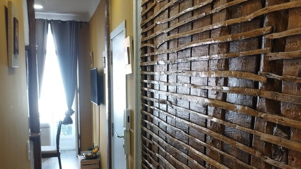 A hallway with wooden blinds, a television mounted on the wall, and a window with curtains. - Lisbon downtown apartment (Lisboa)