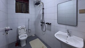 Kylpyhuone, jossa on wc, bidee, suihku, pesuallas ja peili.