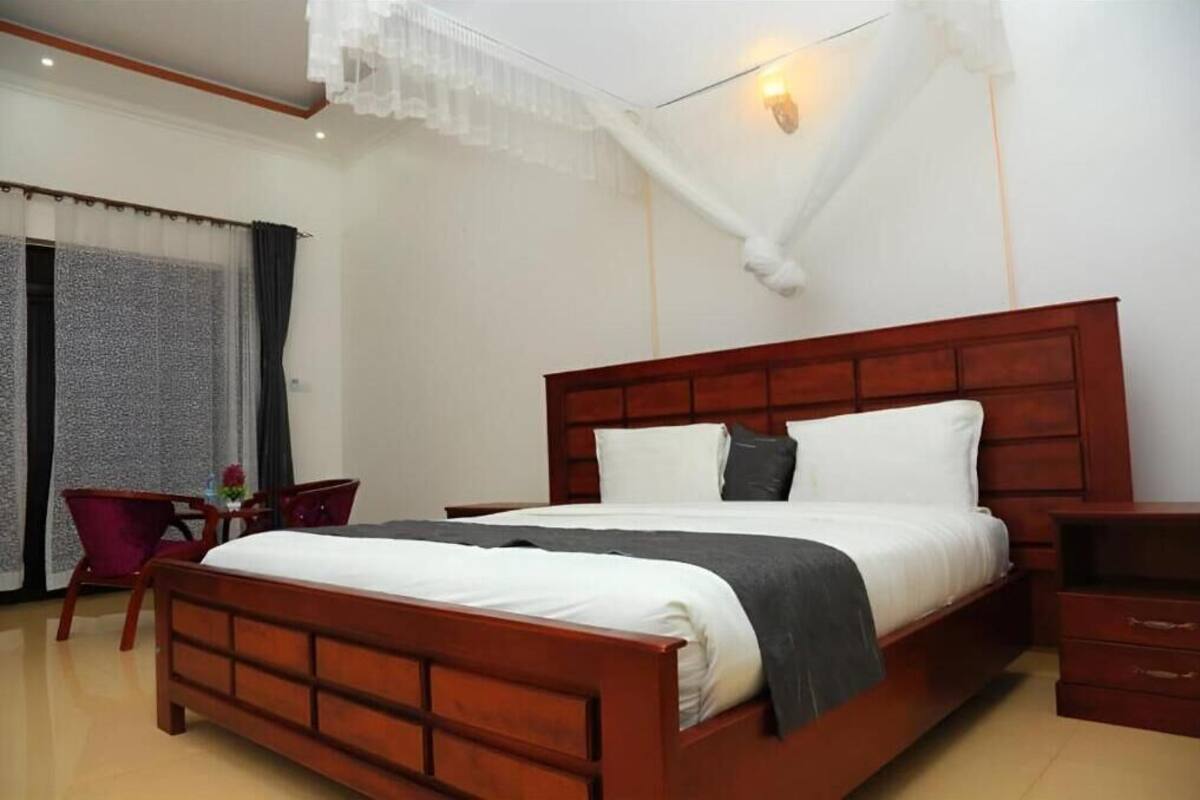 A bedroom with a wooden bed, a nightstand, a chair, and a table with a vase.