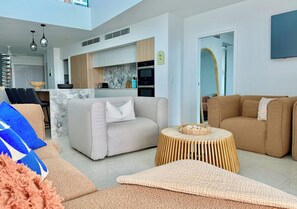 Ein modernes Wohnzimmer mit einer Couch, einem Couchtisch und einer Küche im Hintergrund.