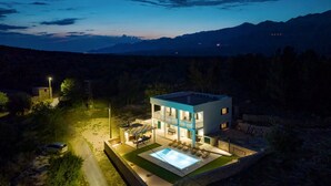 A modern two-story house with a swimming pool, surrounded by a natural landscape and mountains in the background. - Krusevo Pool Villa For 10 (Obrovac)