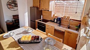 Cocina compacta con armarios de madera, horno empotrado y un amplio ventanal que proporciona luz natural.