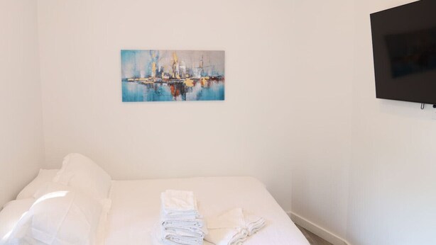 Ein Hotelzimmer mit einem Bett, einem Gemälde und einem Fernseher.
