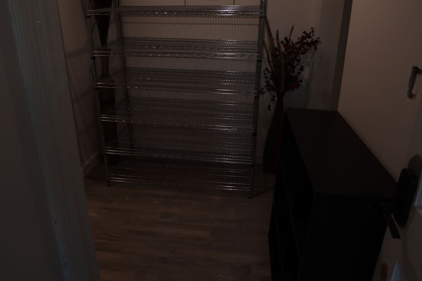 A hallway with a metal rack, a wooden floor, and a dark-colored table.