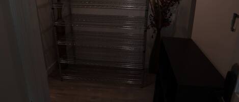 A hallway with a metal rack, a wooden floor, and a dark-colored table.
