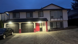 A two-story house with a garage, a red door, and a driveway.
