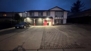 Una casa de dos pisos con garaje, entrada para coches y una zona pavimentada al frente.