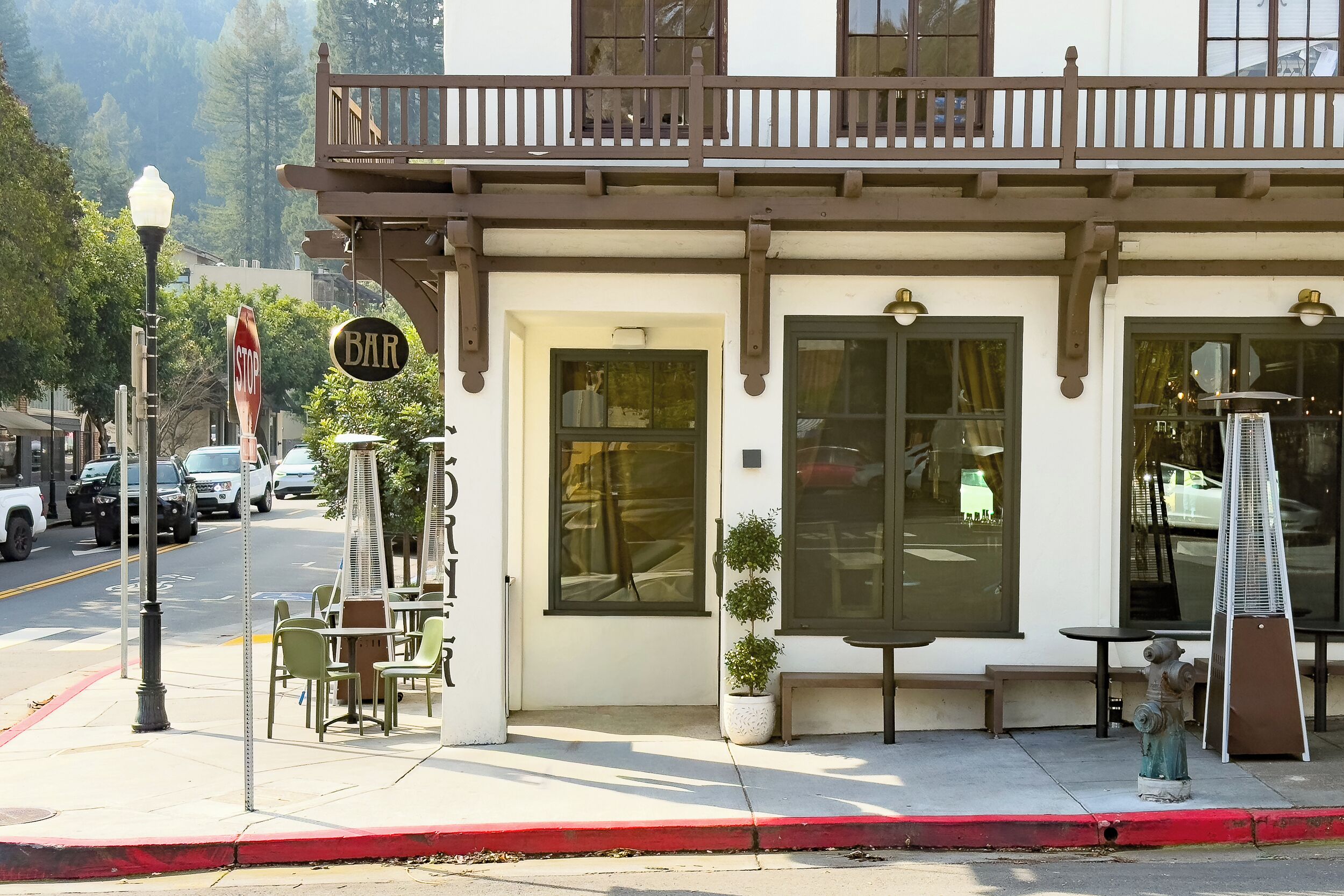 A building with a balcony, a 'BAR' sign, and outdoor seating.