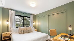 Une chambre bien rangée, avec un lit, un bureau et une chaise.