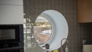 Een keuken met een ronde spiegel die uitzicht op een strand weerspiegelt, een spoelbak en een fornuis.