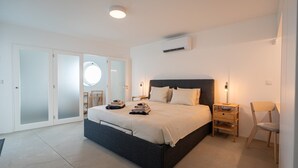 Een moderne slaapkamer met een groot bed, een nachtkastje, een stoel en een ronde spiegel.