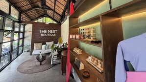 Una boutique dall'arredamento in legno, con un cartello che recita 'THE NEST BOUTIQUE' e scaffali che espongono gioielli e accessori.