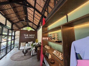A boutique with a wooden interior, a sign reading 'THE NEST BOUTIQUE,' and shelves displaying jewelry and accessories. - Jungle Nest Resort (General Luna)
